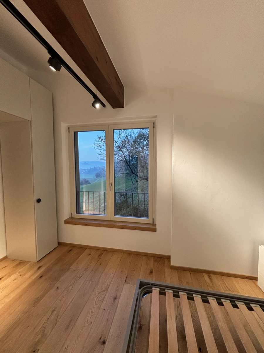 Finestra a doppia anta in alluminio bianco perfetta per una casa di montagna abbinata con il parquet e le travi in legno