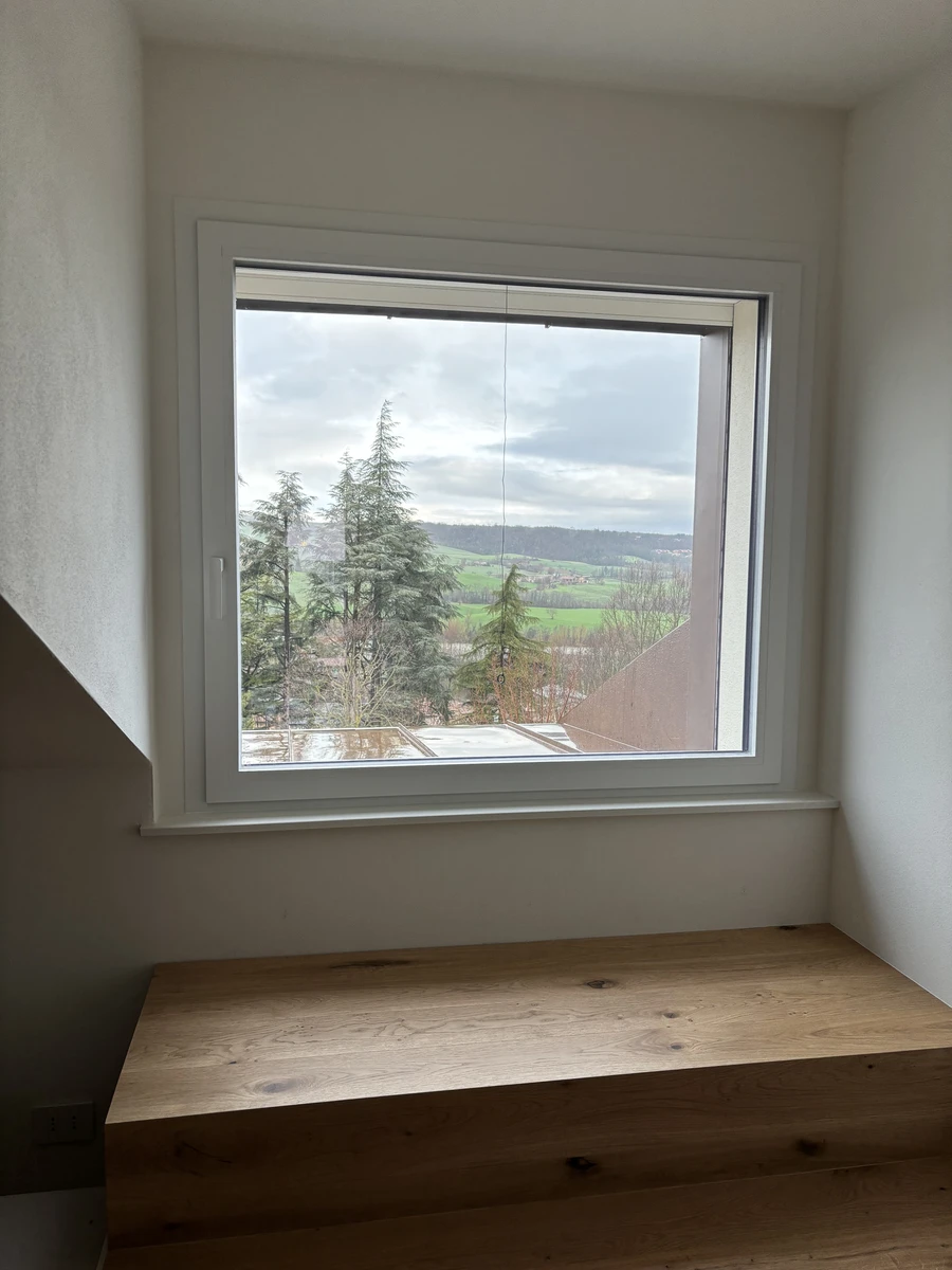 Grande finestra ad anta unica in alluminio bianco con elevato isolamento termico adatta per case di montagna per migliorare il comfort abitativo