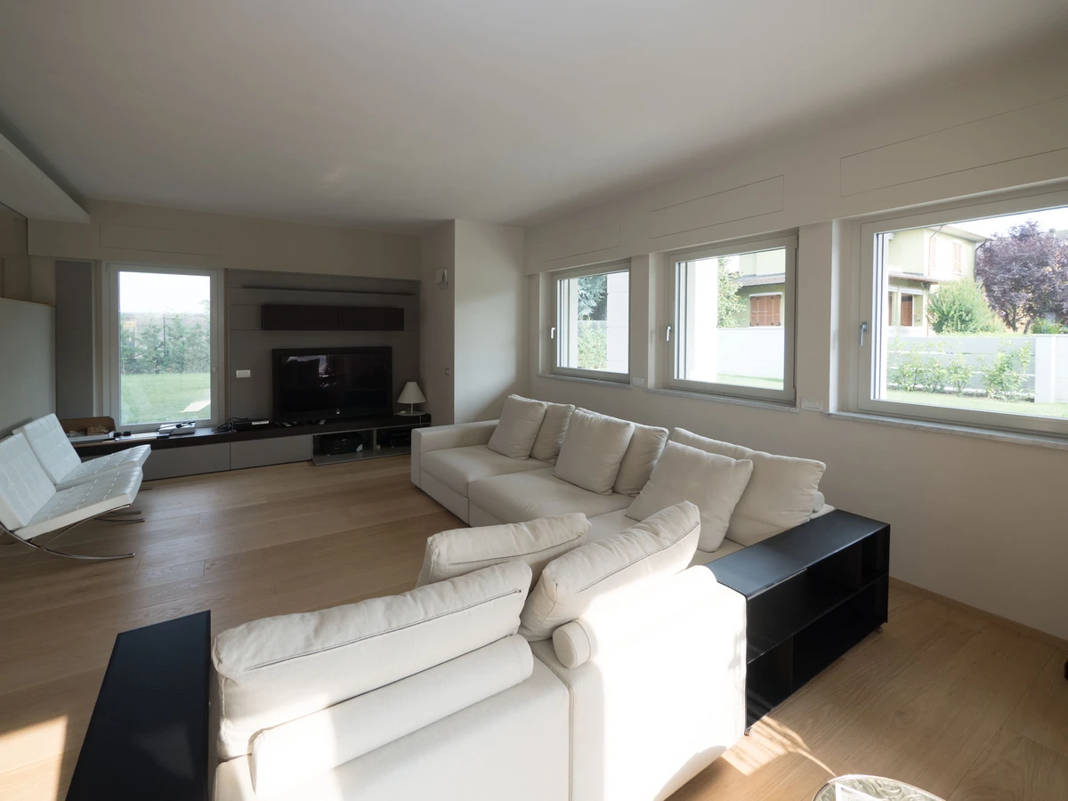 Grandi finestre in alluminio ad unica anta per dare luce alla sala di una casa indipendente a piacenza