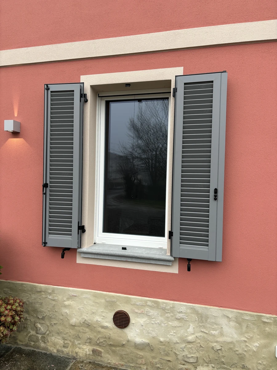 Persiana in alluminio per finestra color grigio abbinata a facciata color rosso opaco
