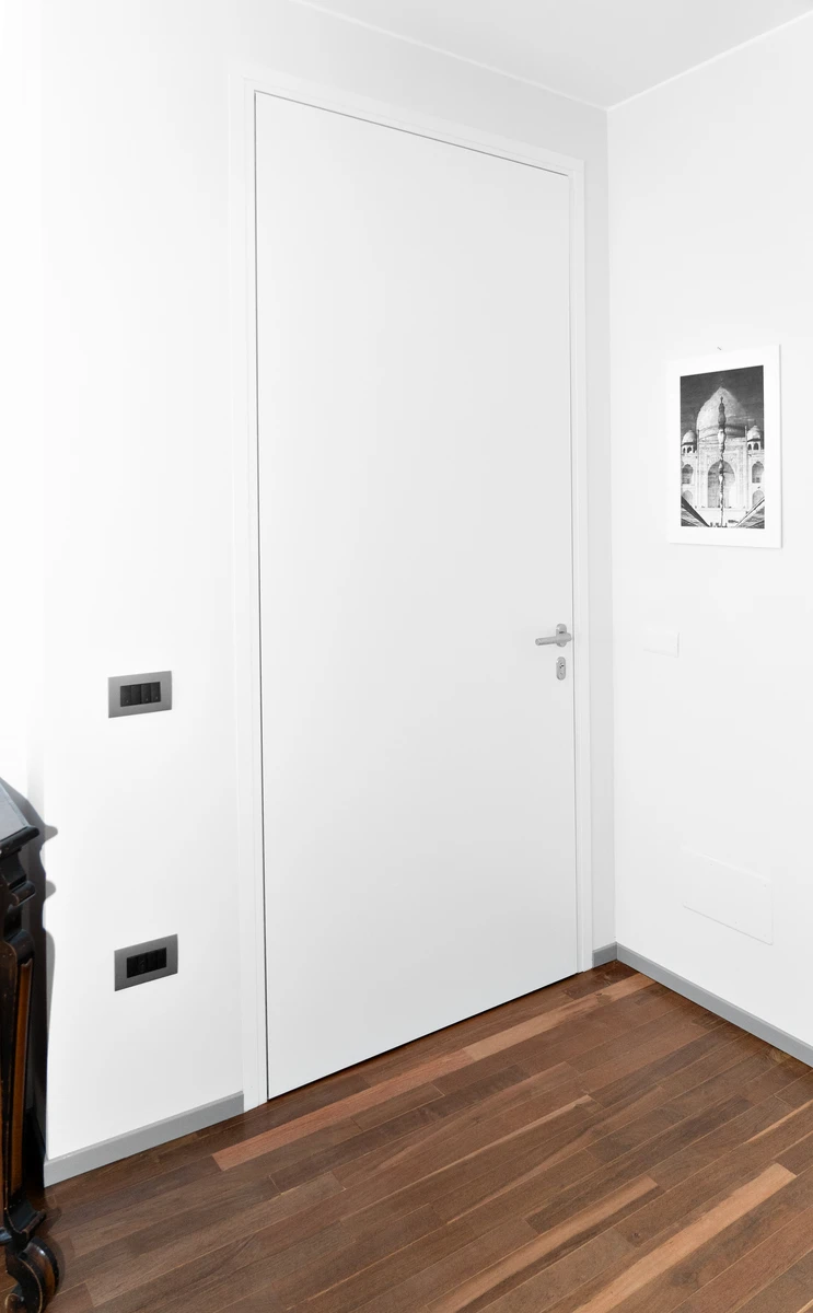 Interno di una porta di ingresso in alluminio bianco con maniglia colore metallico discreta ed elegante