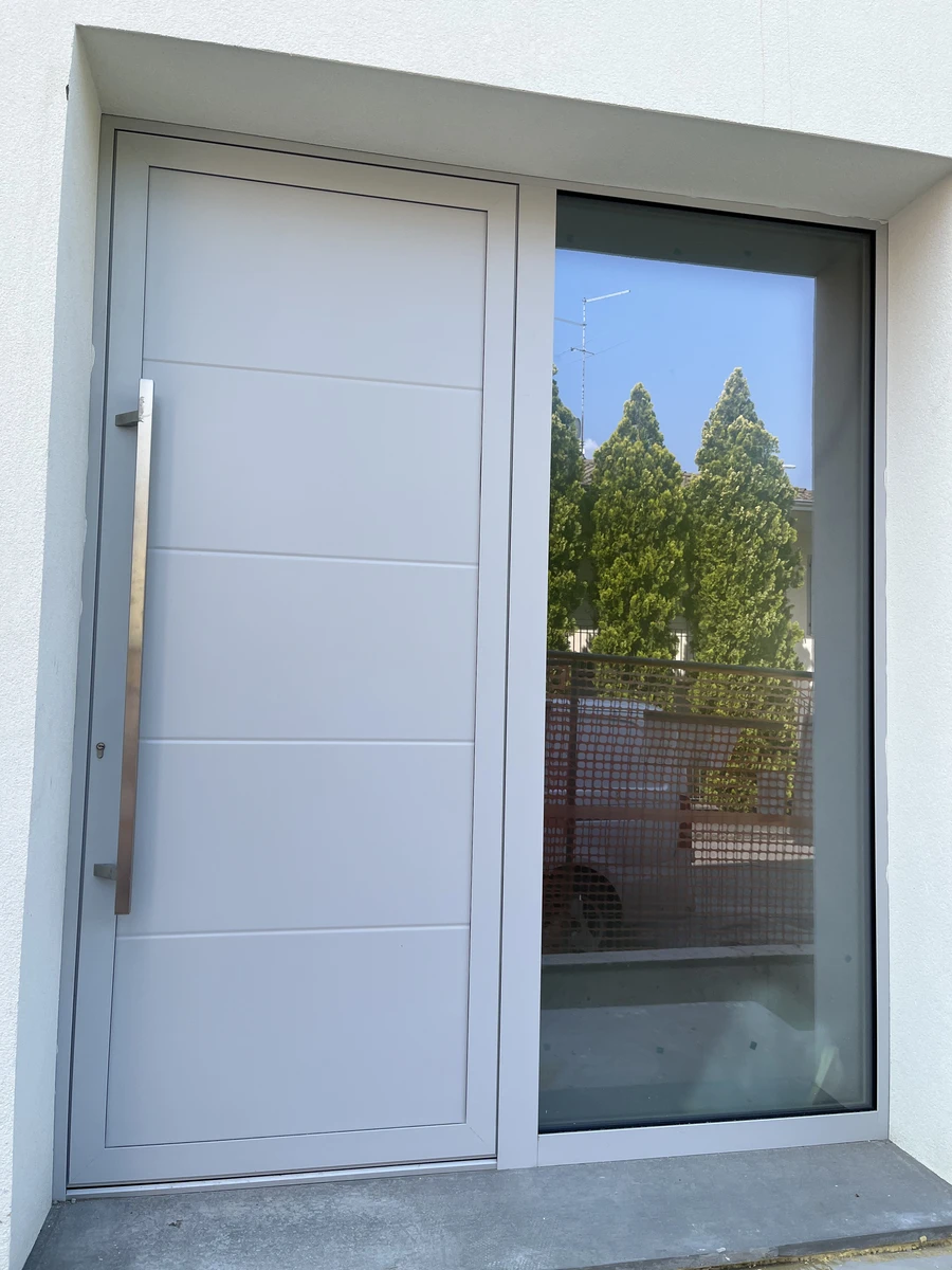 Porta di ingresso con una sezione in alluminio e una sezione in vetro opaco discreta ed elegante