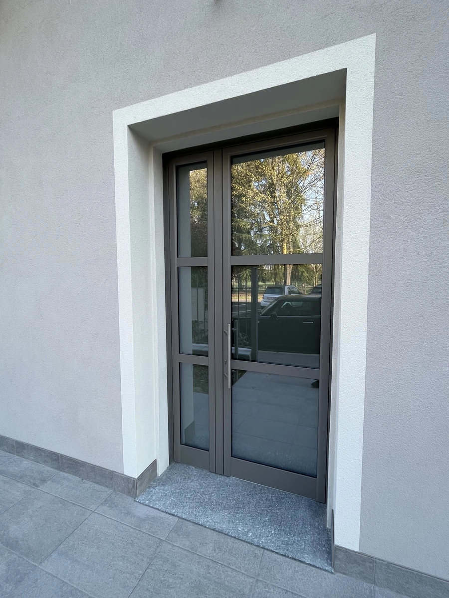 Portone di ingresso per condominio a piacenza con profili in alluminio grigio e vetri semiopachi