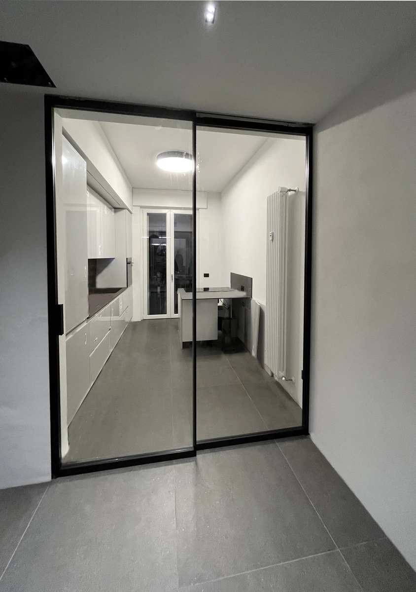 Ampia porta scorrevole interna per cucina con vetro trasparente e telaio nero sottile