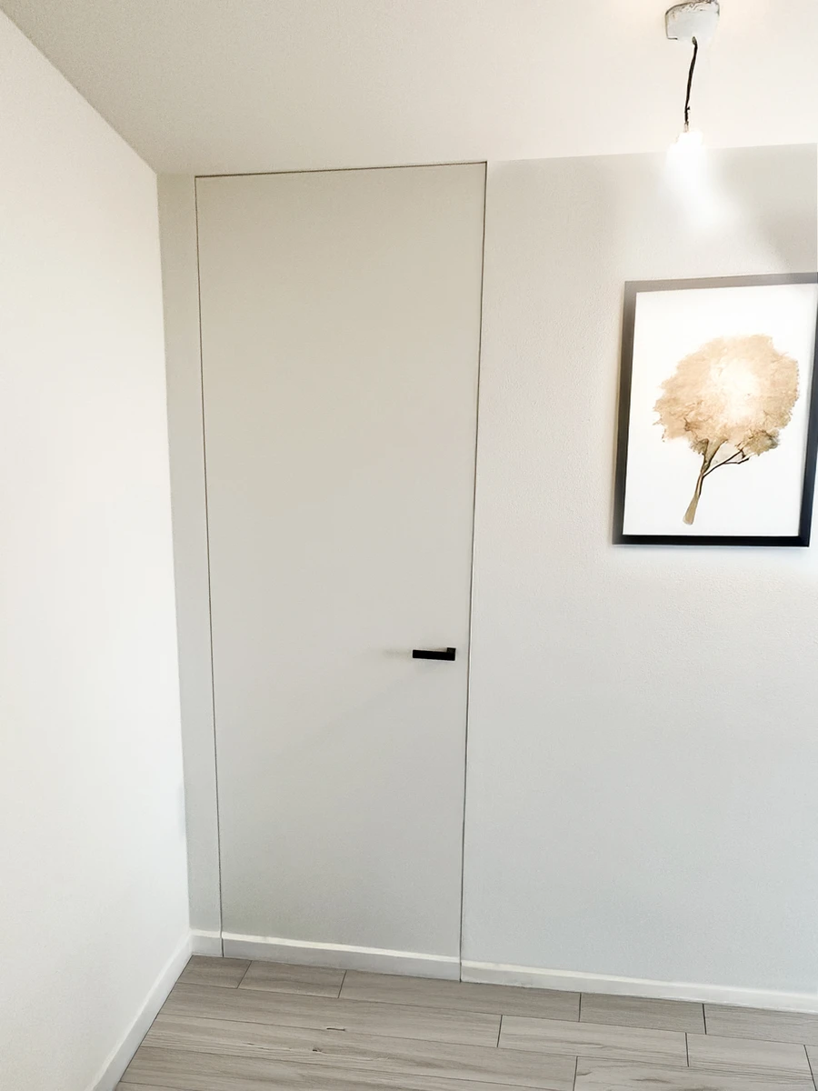 Porta laccata bianca liscia con cerniere a scomparsa e maniglia nera adatta ad una casa moderna con stile minimal